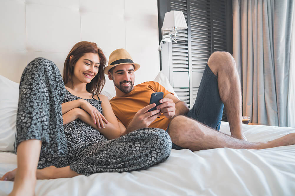 A couple uses a smartphone app in their hotel